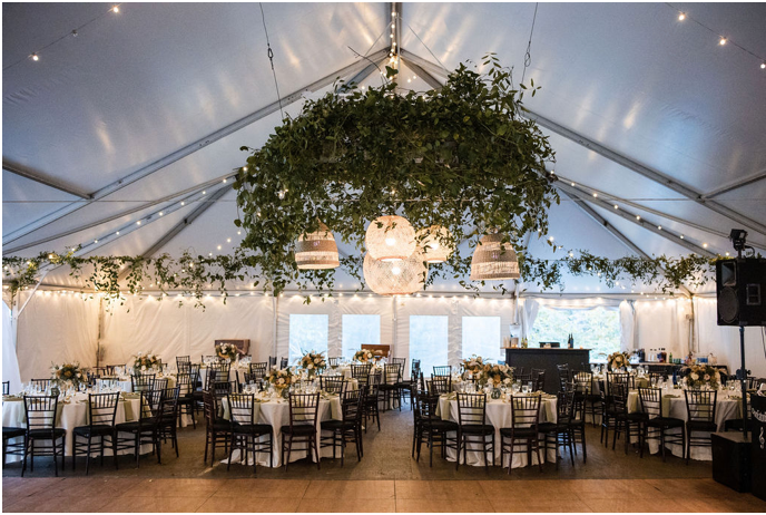 A large tent with tables and chairs set up for a wedding reception.