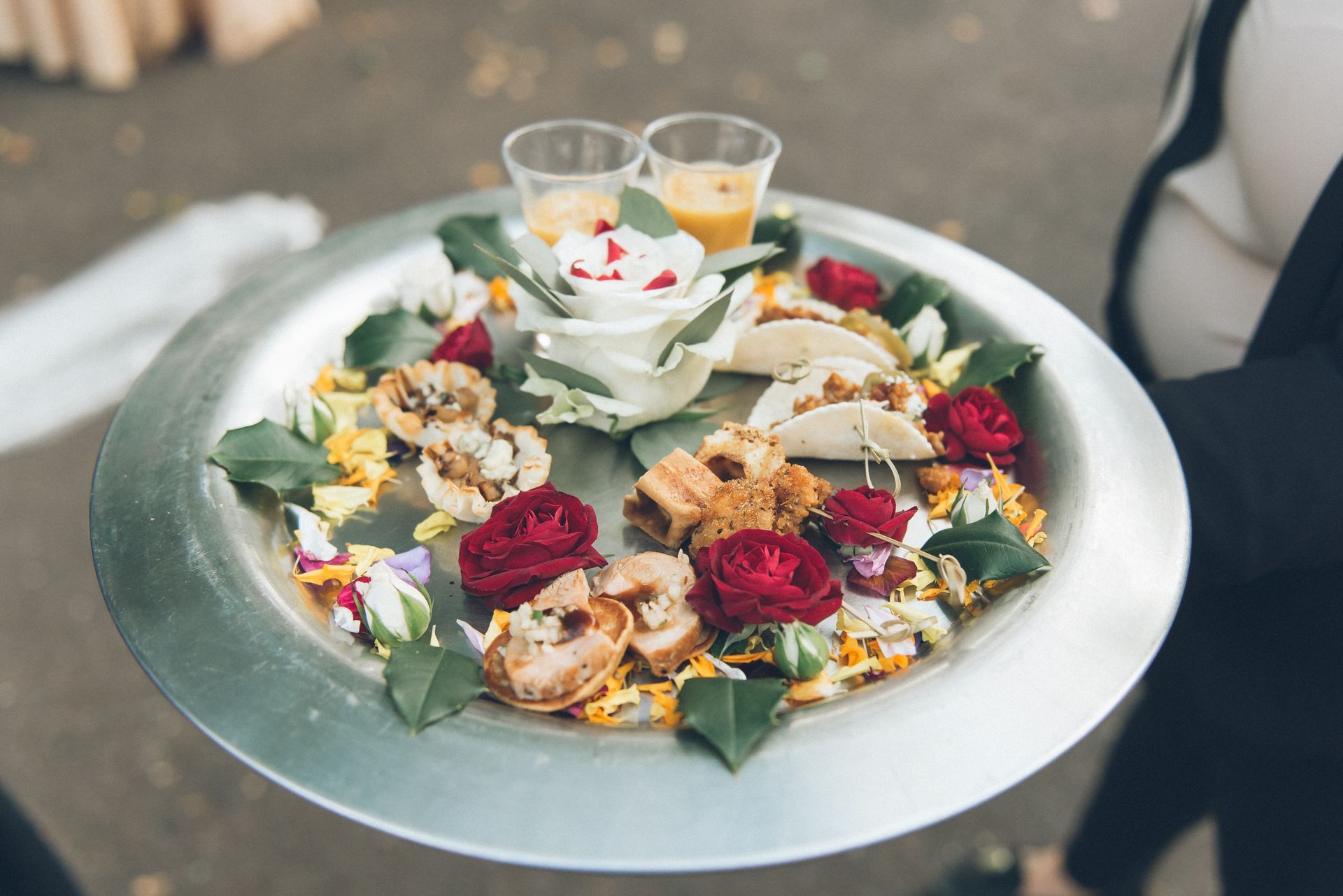 A person is holding a tray of food with flowers on it.