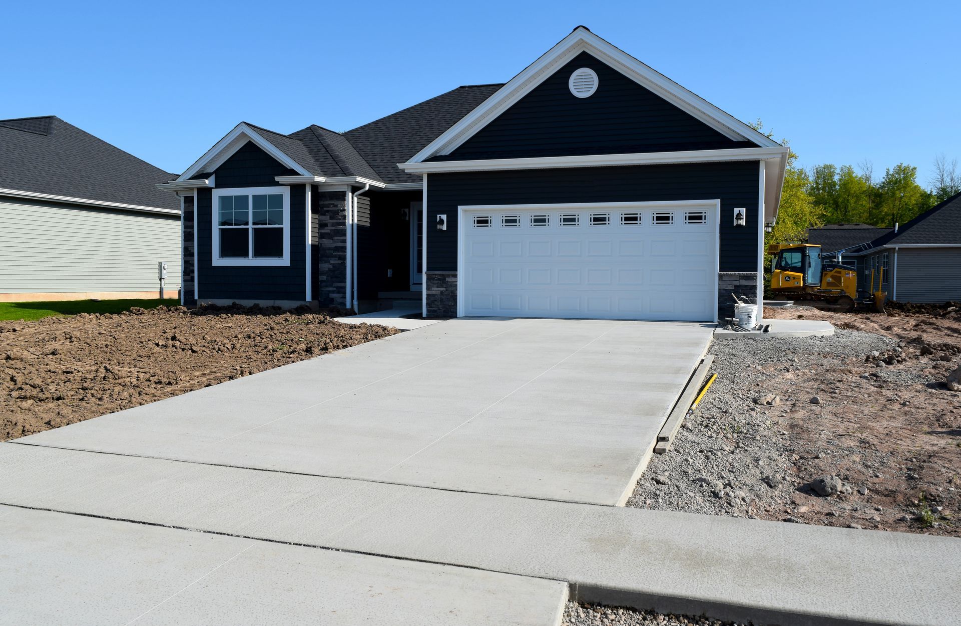 New construction, single-story house with blue siding, white garage door, and concrete driveway.