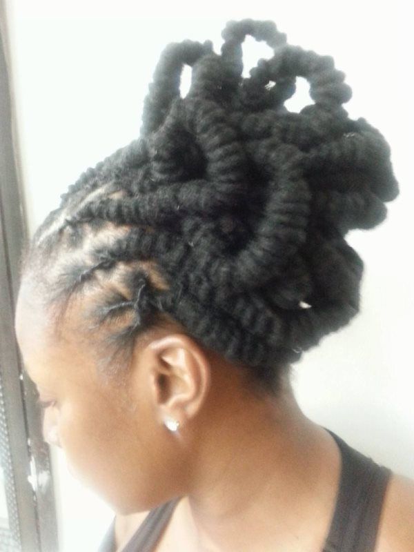 Side profile of a person with braided hair styled into a large bun near a window.