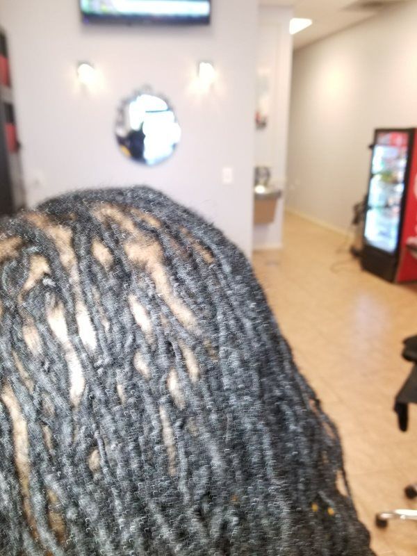 Close-up of braided hair in a bright indoor room with wall decor and a vending machine in the background