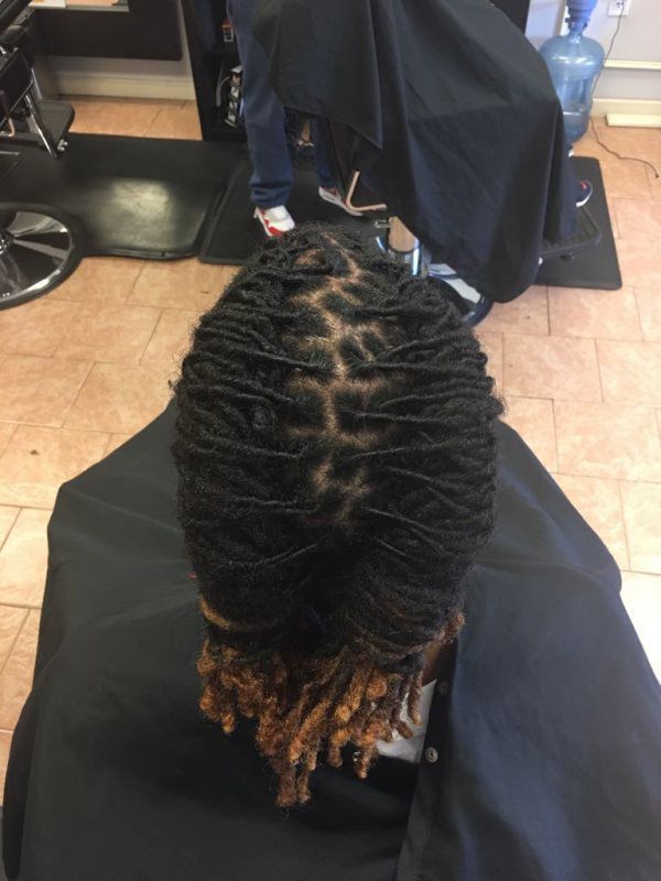 Top view of twisted braids being styled in a salon chair, with a stylist in the background.