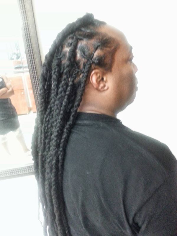 Side profile of a person with long braided hair wearing a black shirt indoors near a window.