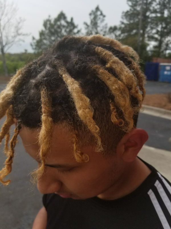 Person with dreadlocks getting hair styled while seated in a chair