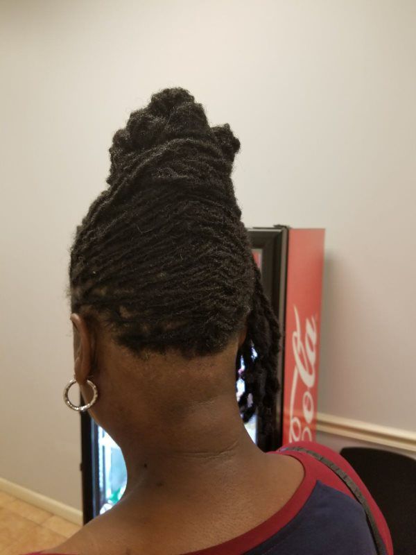 Person with braided updo and hoop earrings standing in front of a Coca-Cola vending machine.