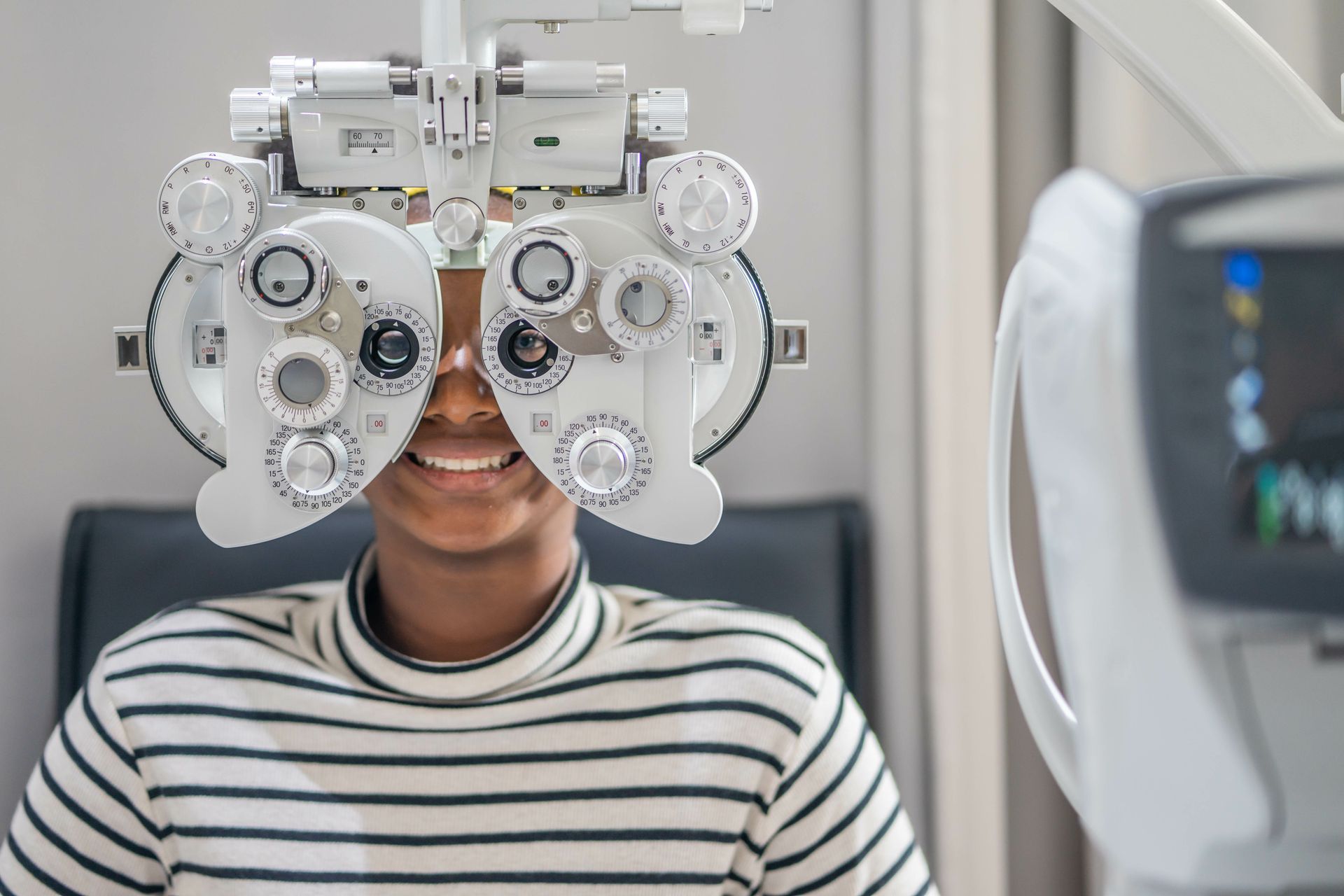 A teen girl goes through an eye test on a phoropter. A teen girl goes through an eye test on a phoropter.