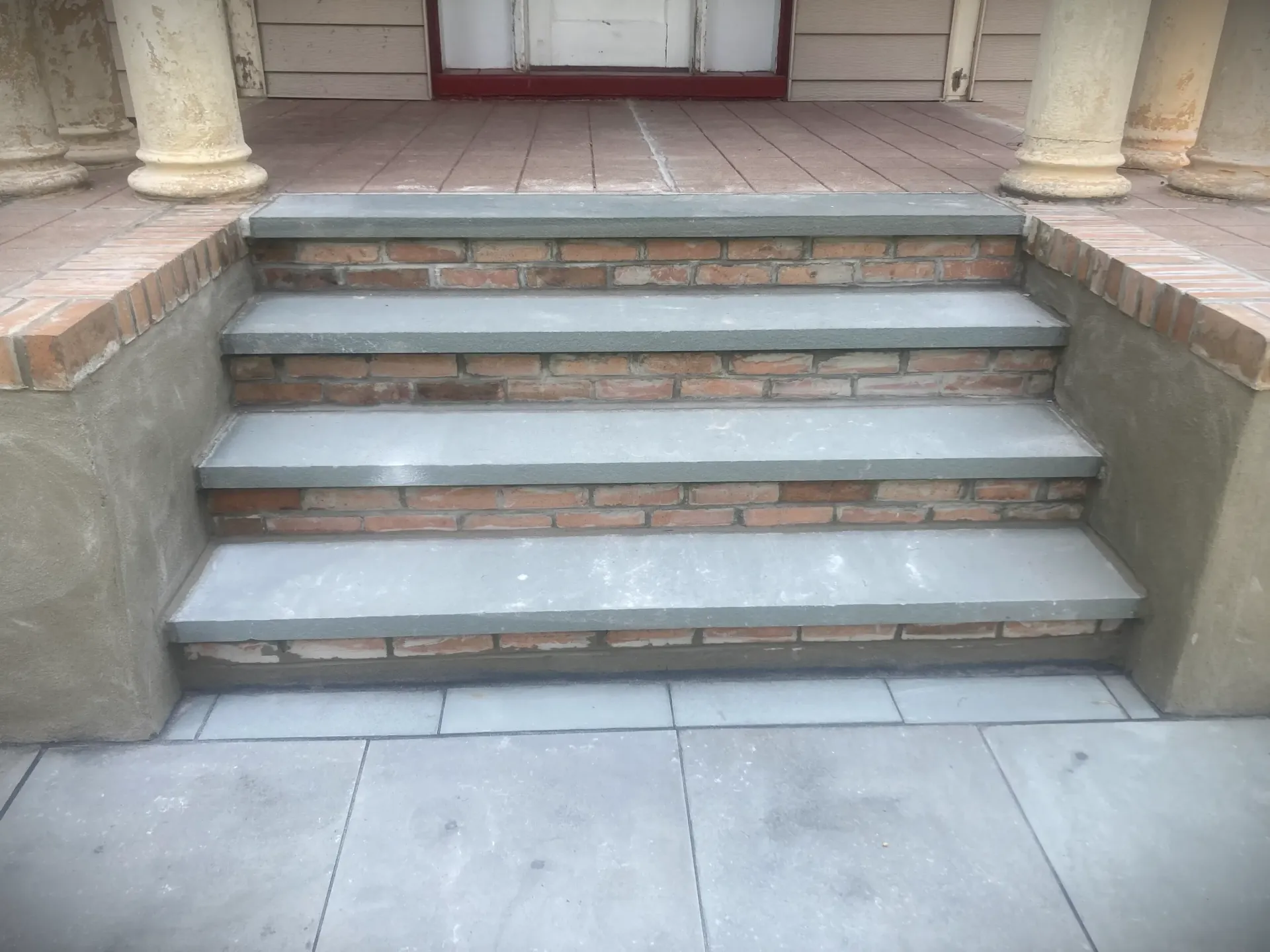 Stone steps leading up to a doorway with columns and tiled porch