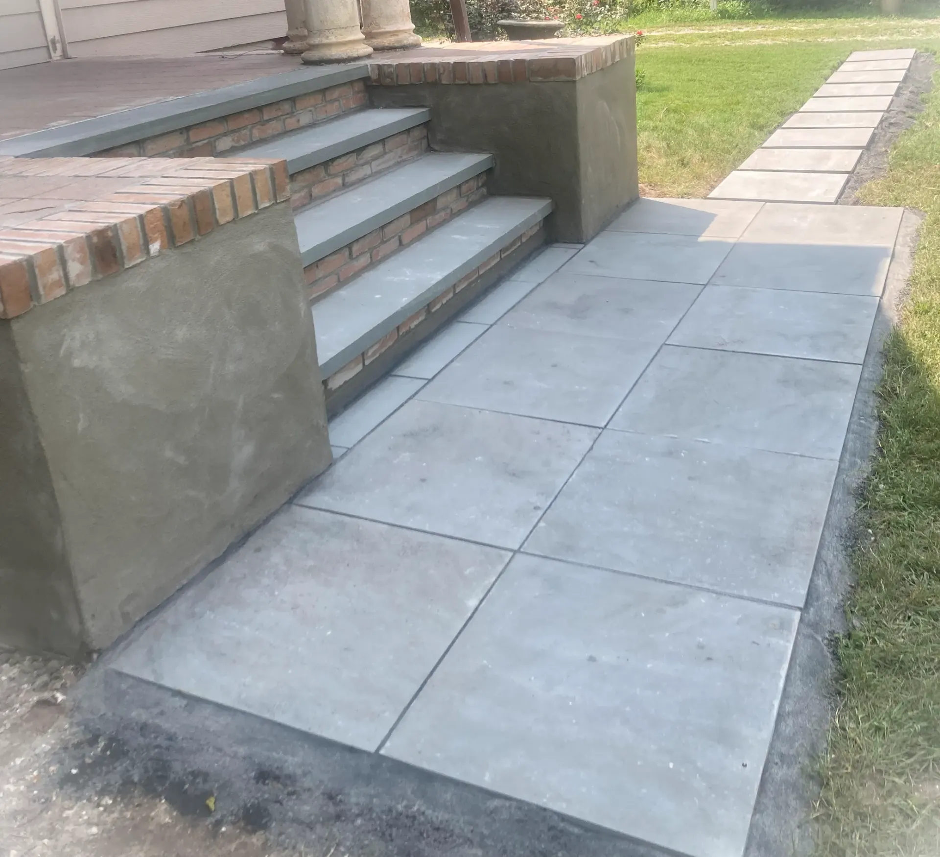 Front steps with a concrete ramp and sidewalk beside a grassy yard