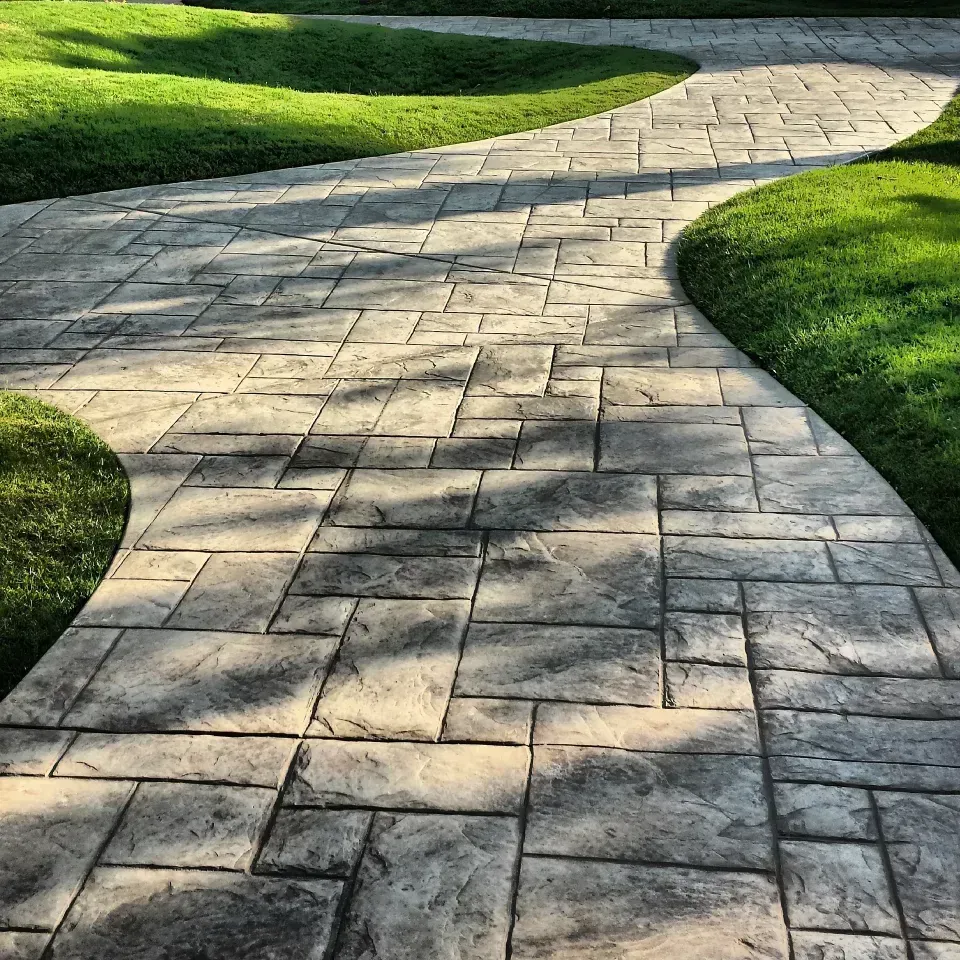 A brick walkway going through a lush green field