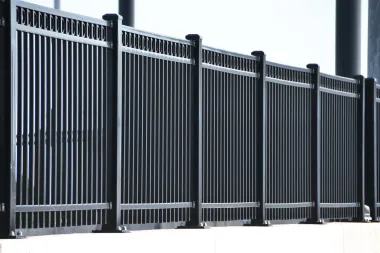 Black metal fence with vertical bars, sectioned with square posts.