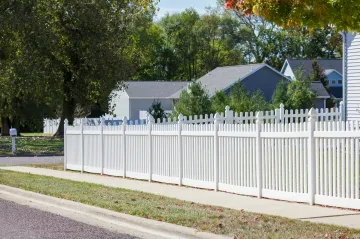 White picket fence along a suburban street, houses in background.