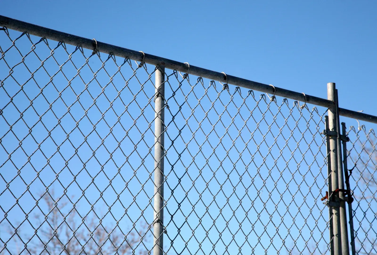 Chain-link fence against a clear blue sky.