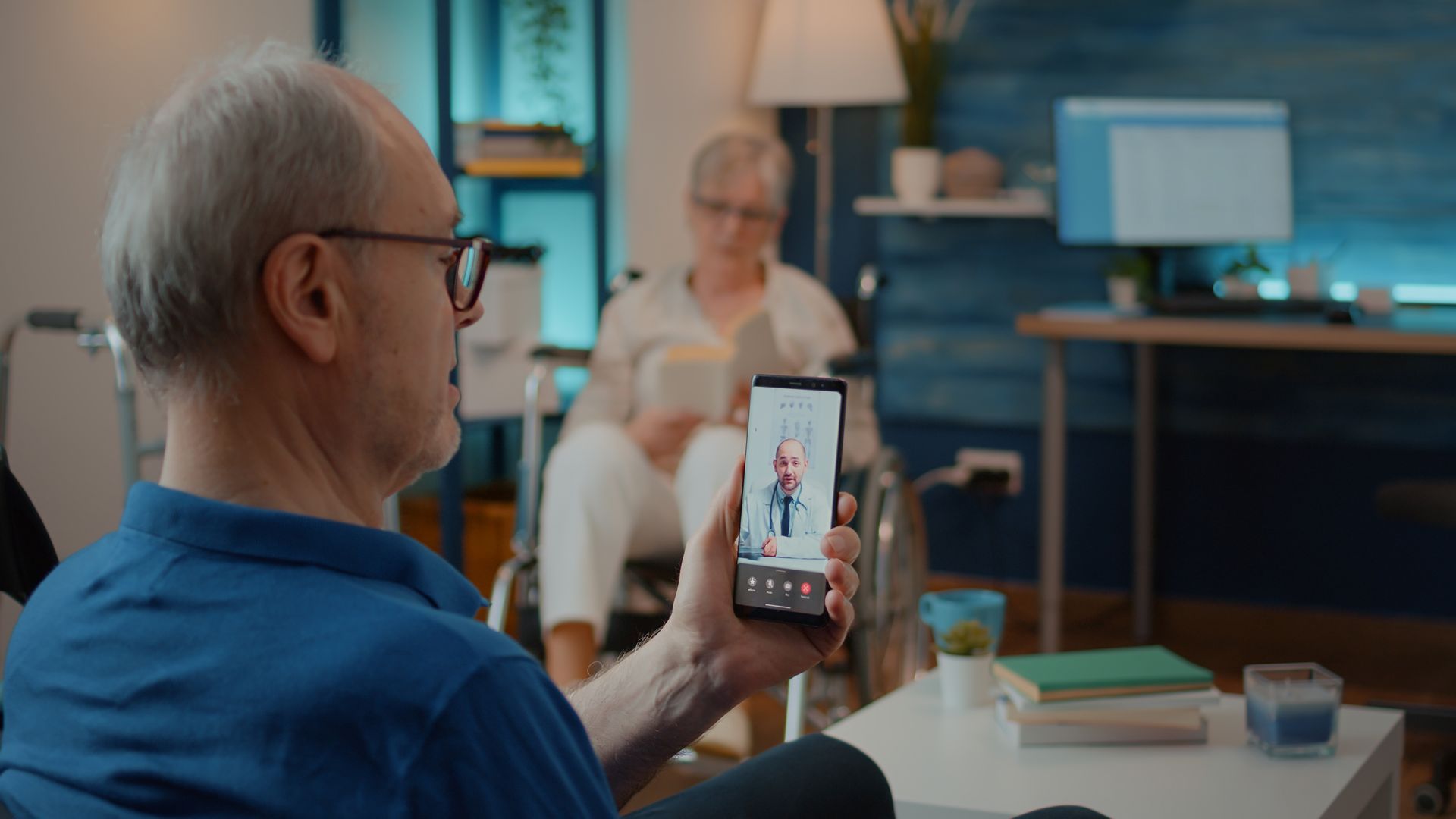 Man holding up a smartphone during a video call with a seated person in a living room