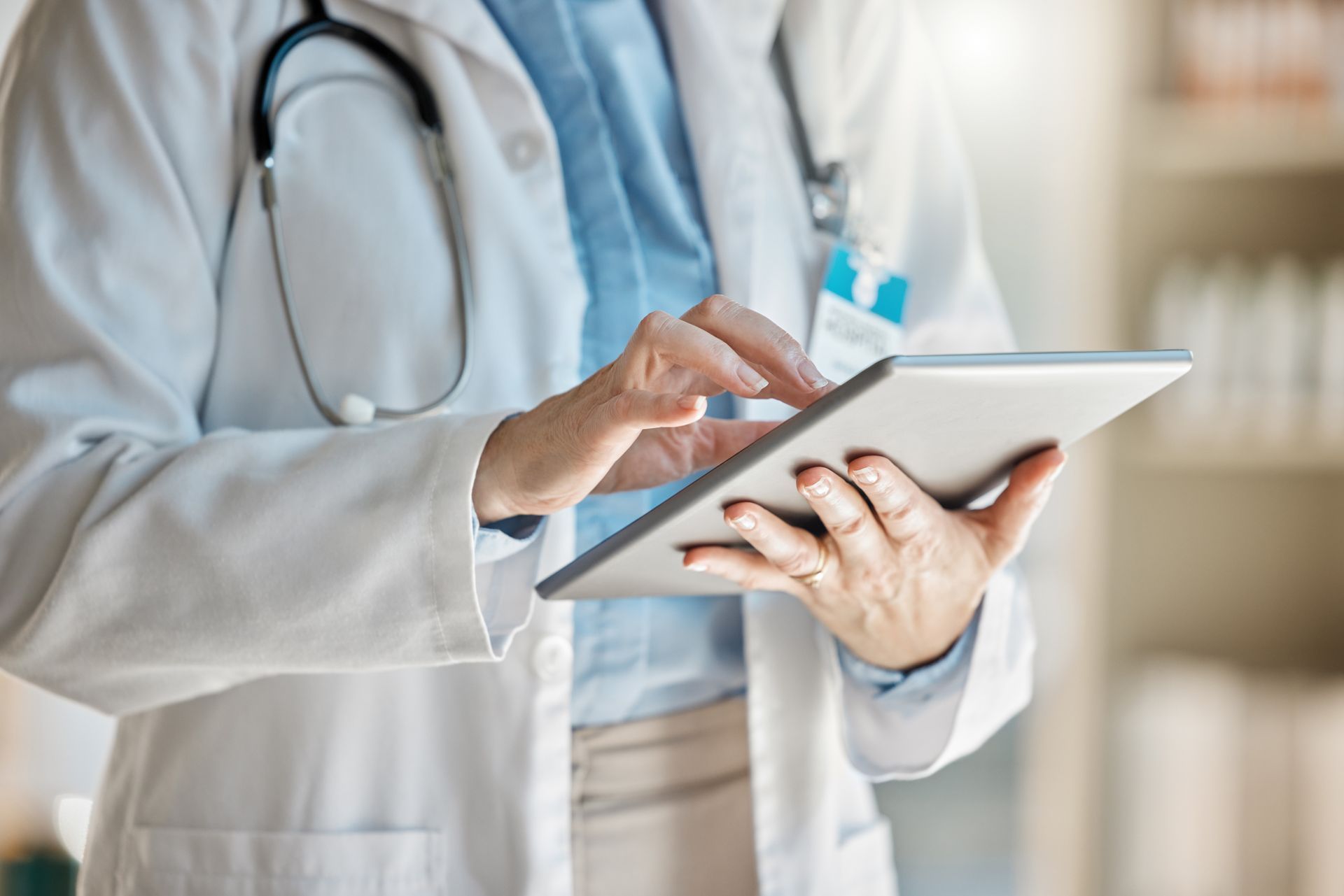 Doctor in white coat using a tablet with a stethoscope around the neck
