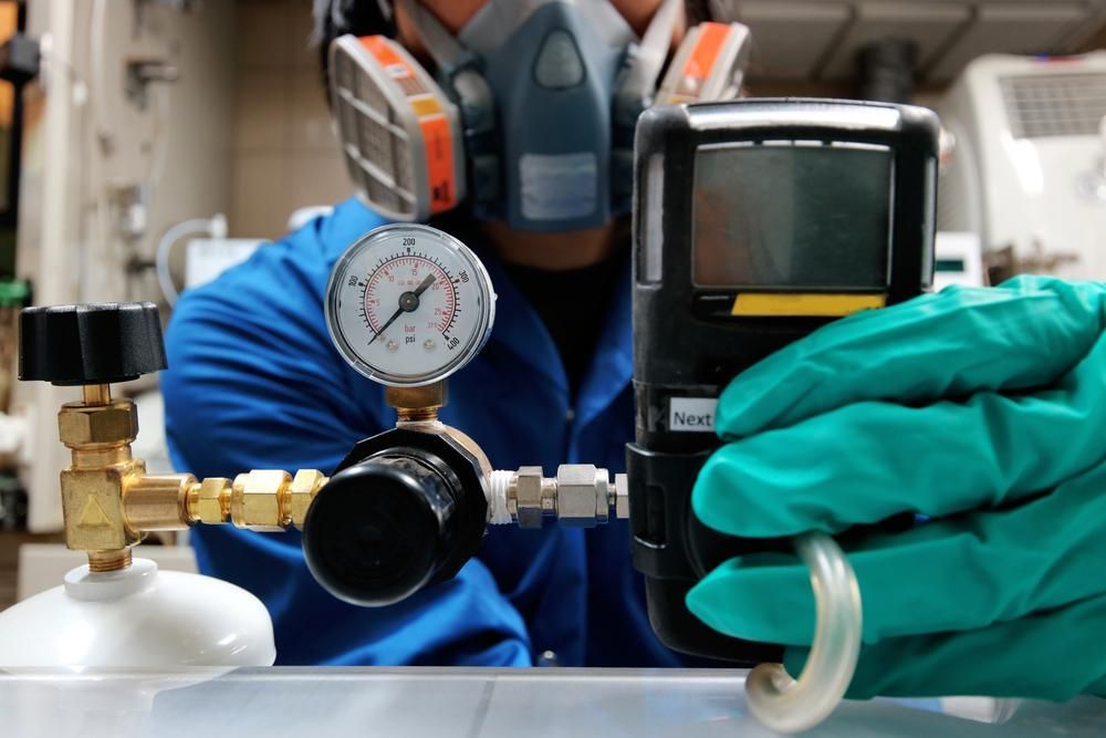 Person in Lab Coat and Respirator, Holding Gas Detector — ABV Plumbing In The entrance, NSW