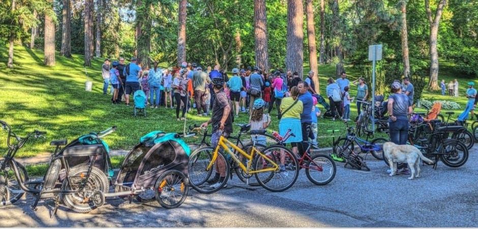 A group of people are standing around bicycles in a park.