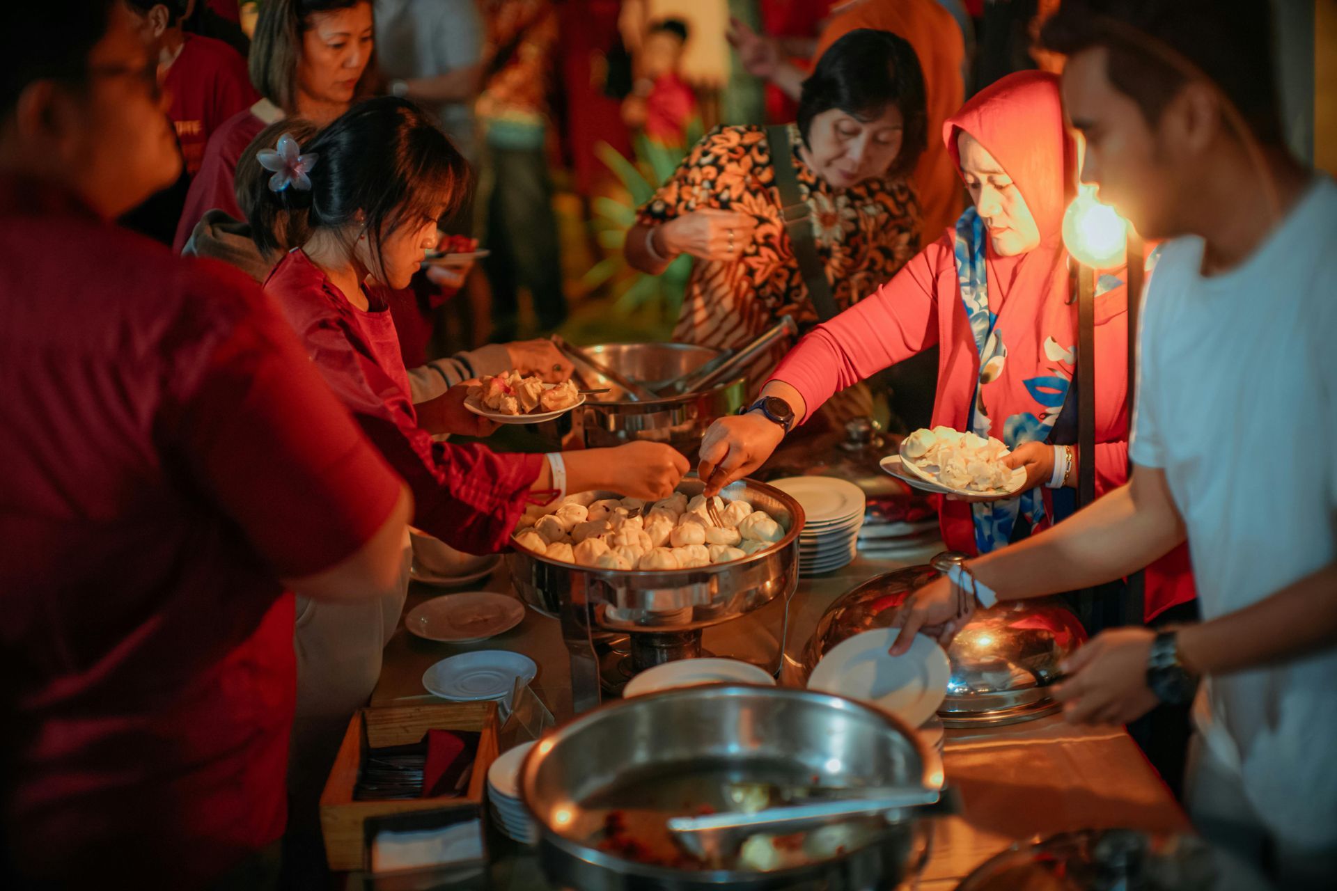 A group of people are standing around a table eating food.