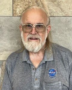 A man with a beard and glasses is wearing a nasa shirt.