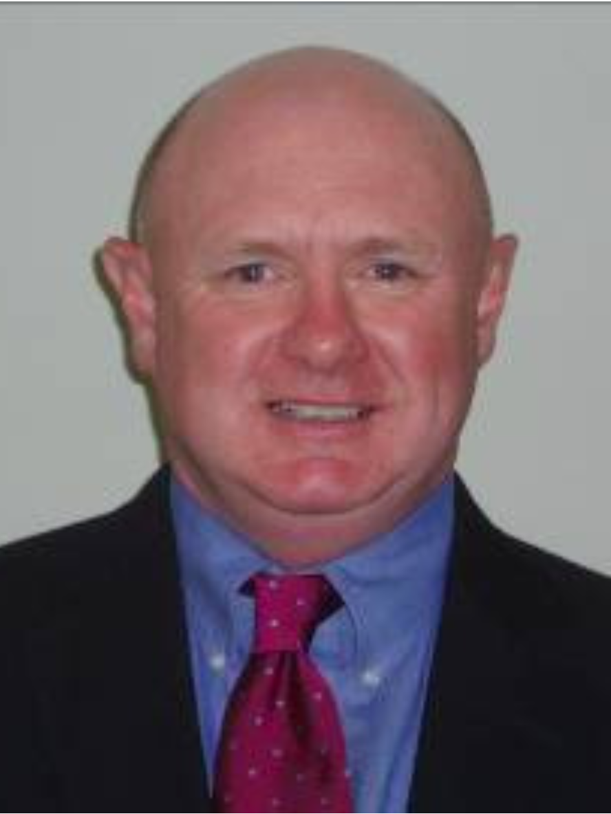 A bald man wearing a suit and tie is smiling for the camera.