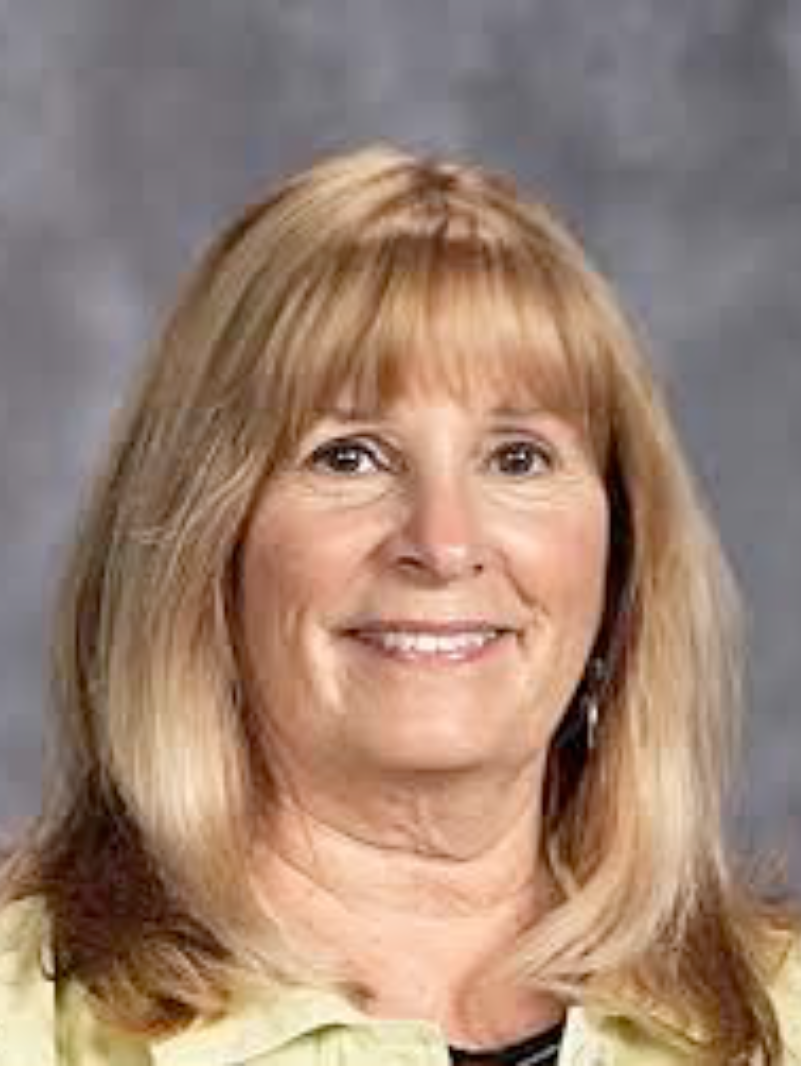 A woman with blonde hair and bangs is smiling for the camera.