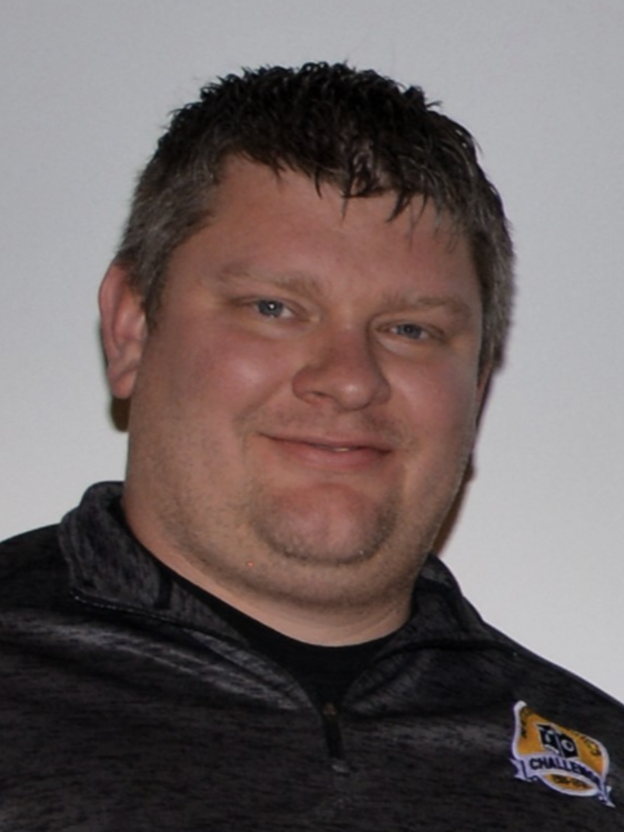 A man wearing a black shirt with a shield on it
