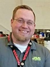 A man wearing glasses and a honda lanyard is smiling for the camera.