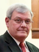 A man in a suit and tie is wearing glasses.