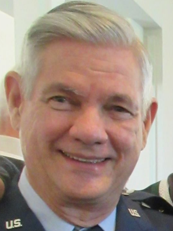 A man in a military uniform is smiling for the camera.