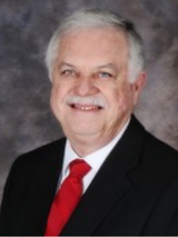 A man in a suit and tie is smiling for the camera.