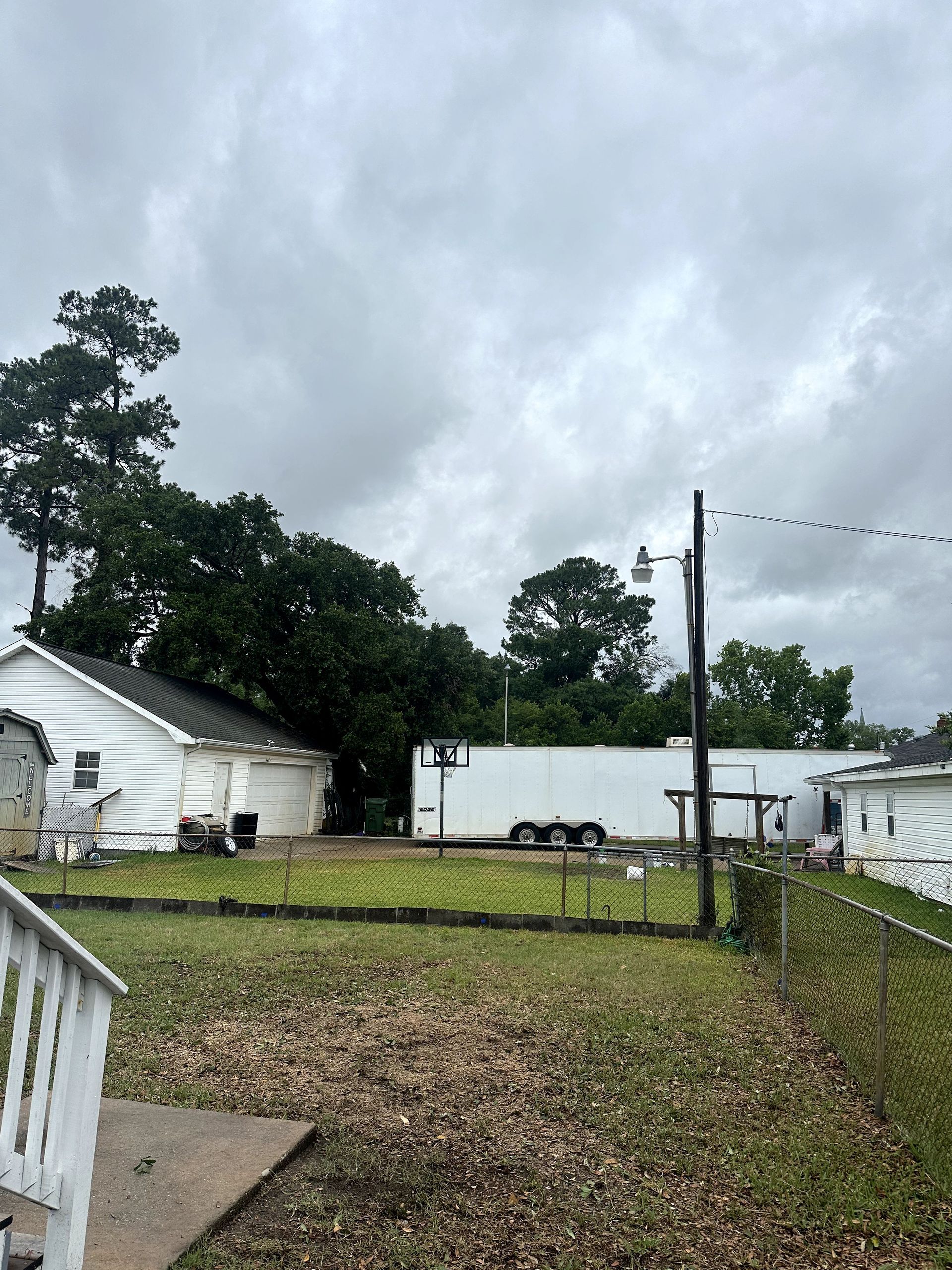 Cloudy backyard with white houses, a grassy yard, and a utility pole with power lines.