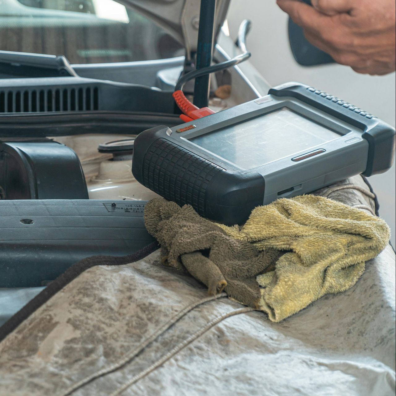 A person is using a diagnostic tool under the hood of a car