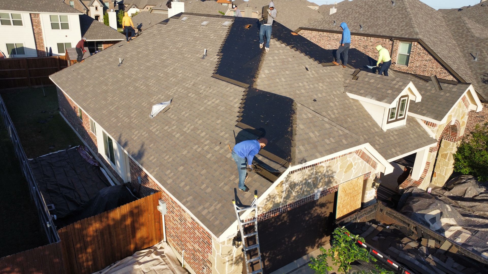 A group of people are working on the roof of a house.