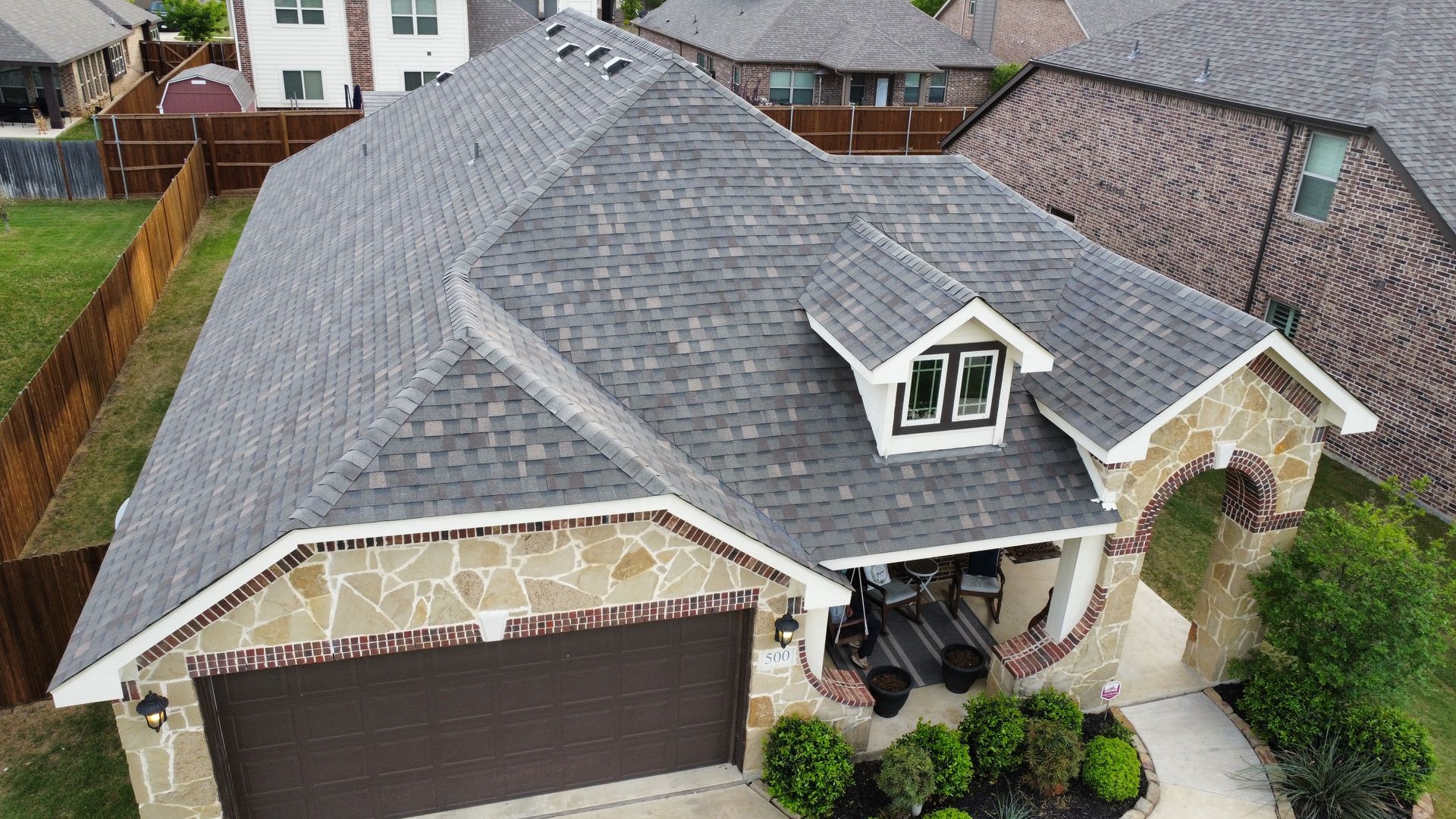 An aerial view of a house with a gray roof and a large garage.