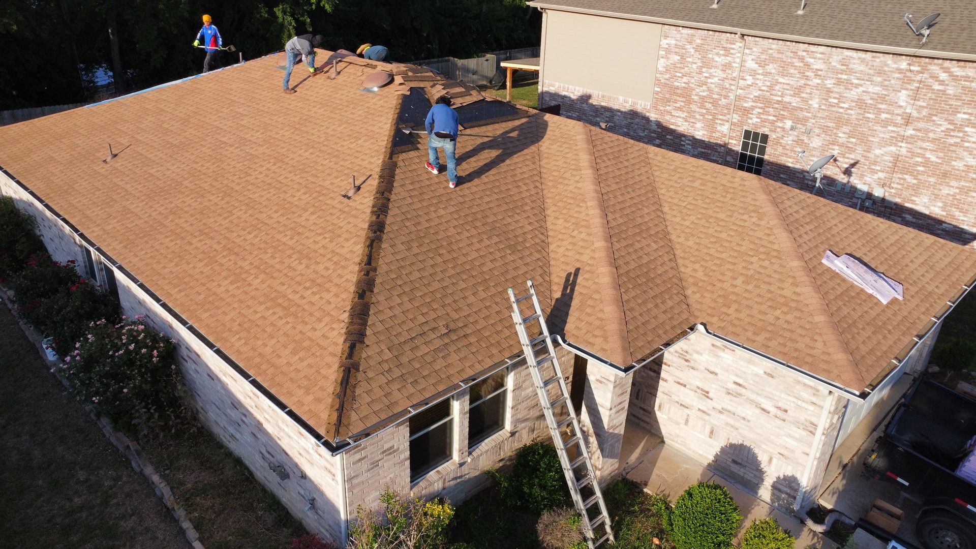 A group of men are working on the roof of a house.