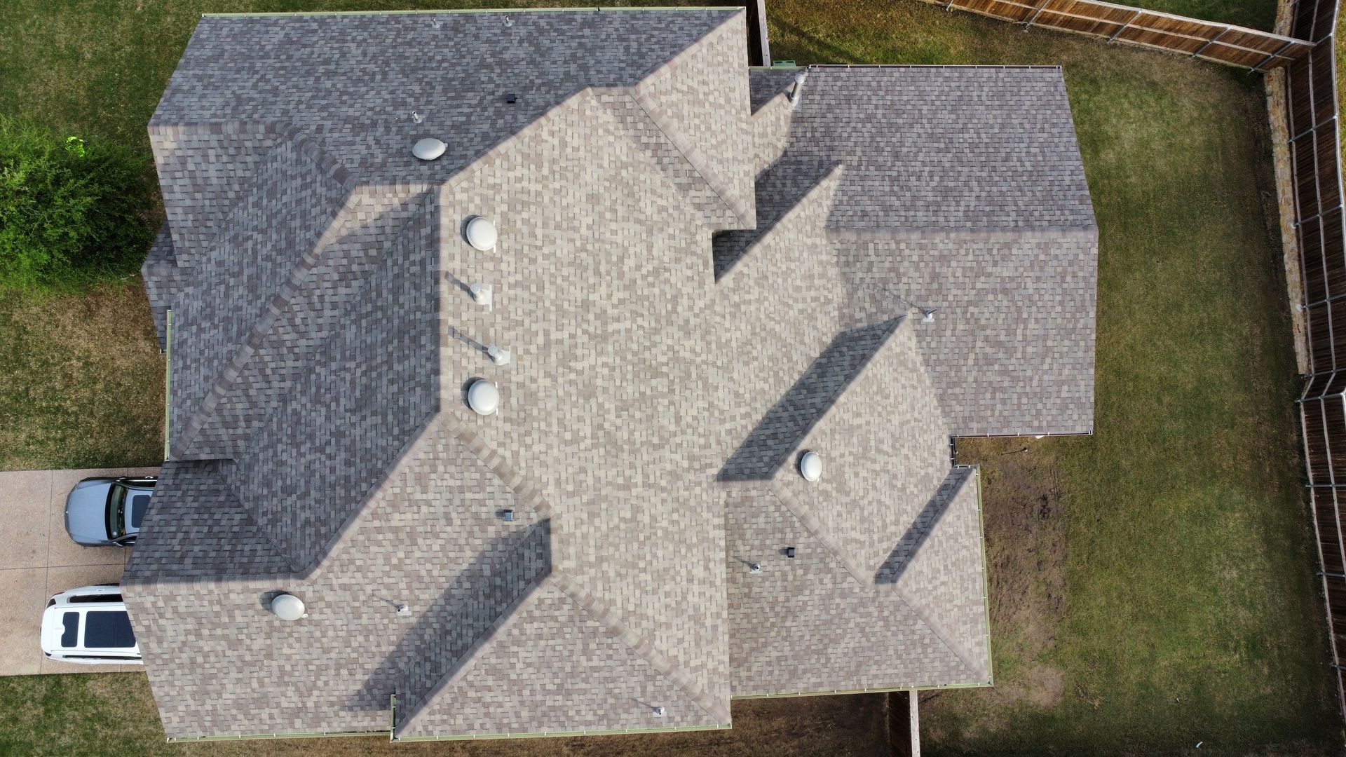 An aerial view of a house with a car parked in the driveway.