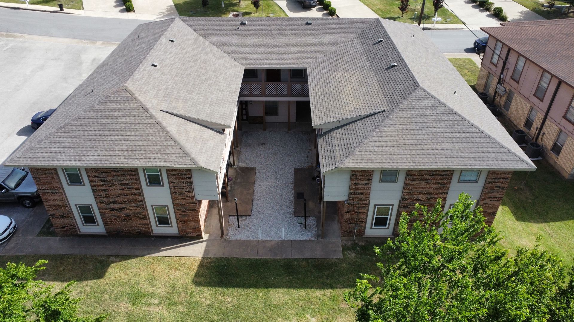 An aerial view of a brick apartment building in a residential area