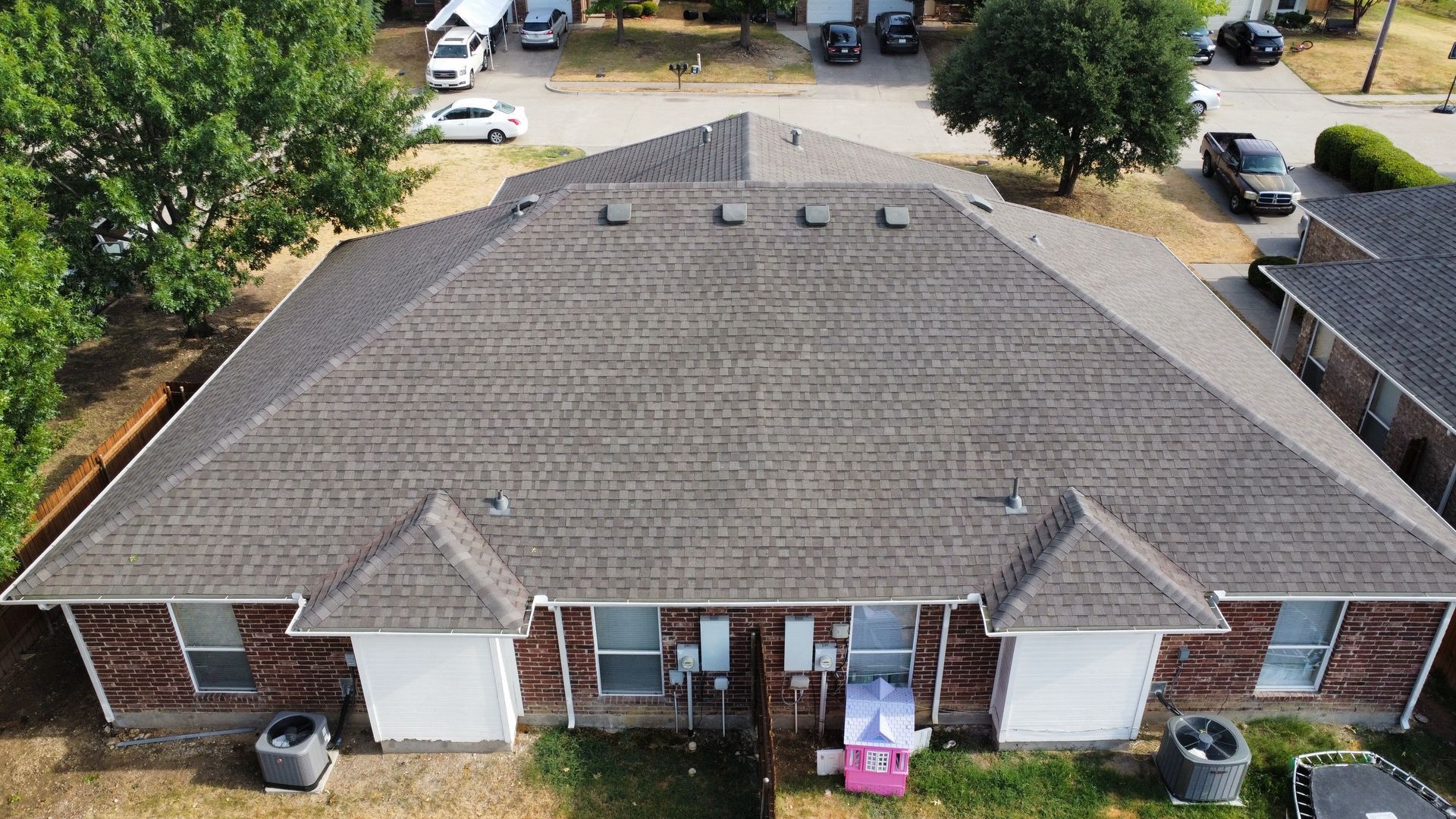 An aerial view of a brick house with a new roof.