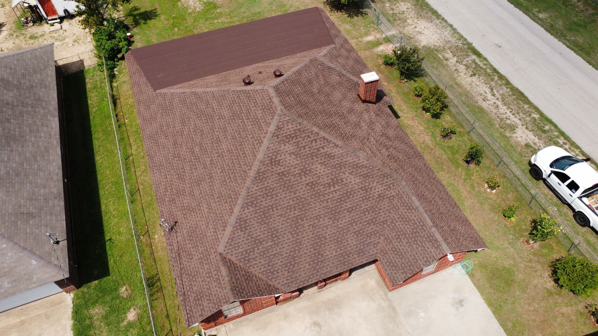 An aerial view of a house with a brown roof and a white truck parked in front of it.