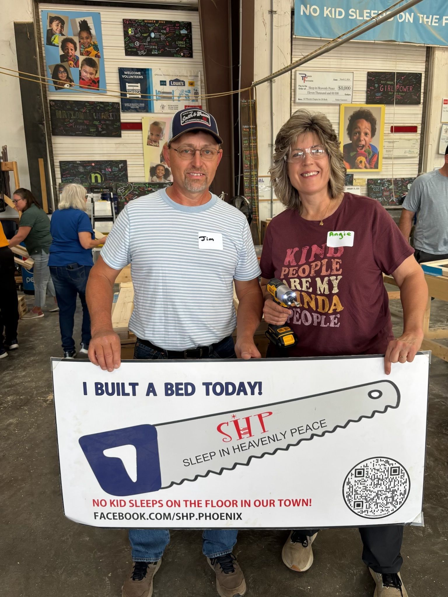 Two FFLC volunteers holding an I Built a Bed Today sign at the workshop