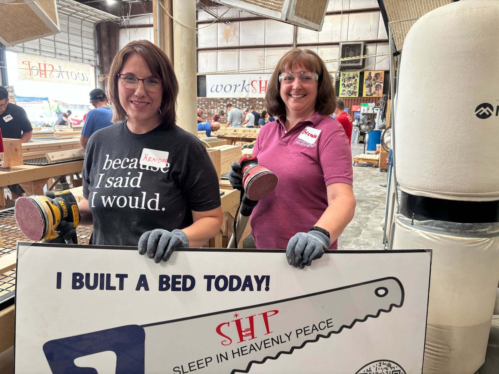 Volunteers with a sander and an I Built a Bed Today sign