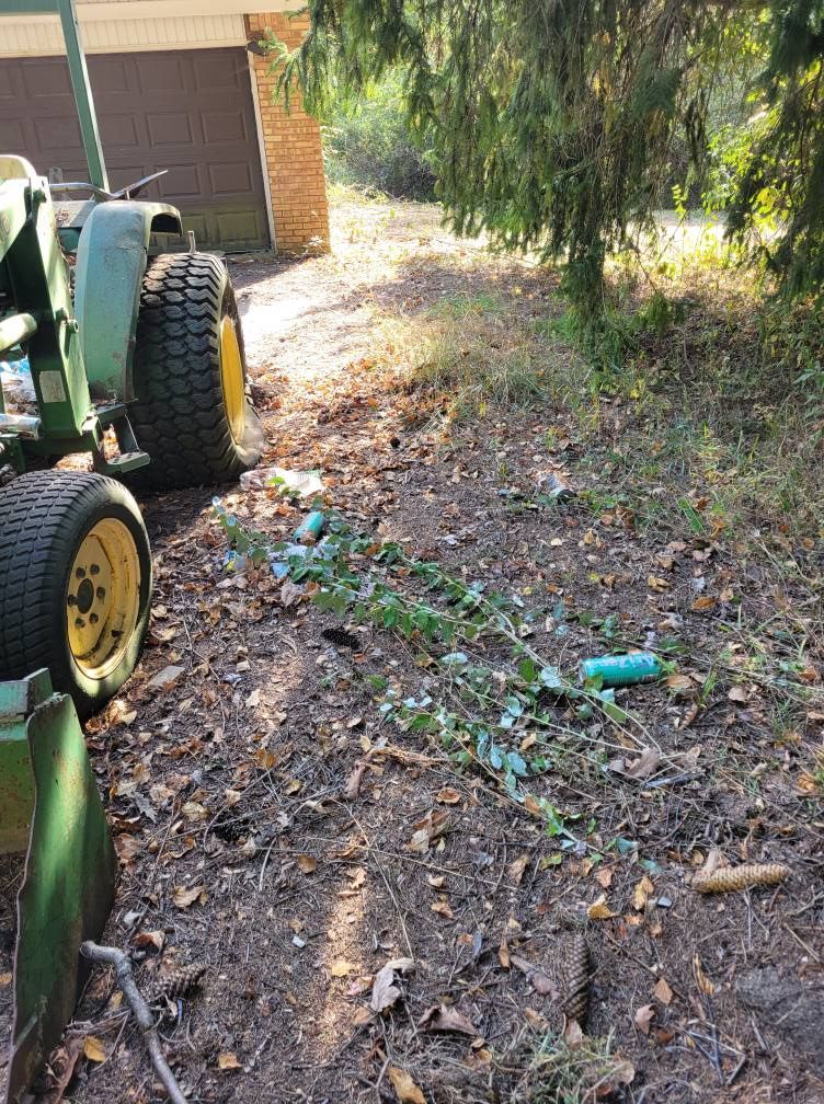 Garden path with scattered debris beside a tractor, under a tree near a brick building.
