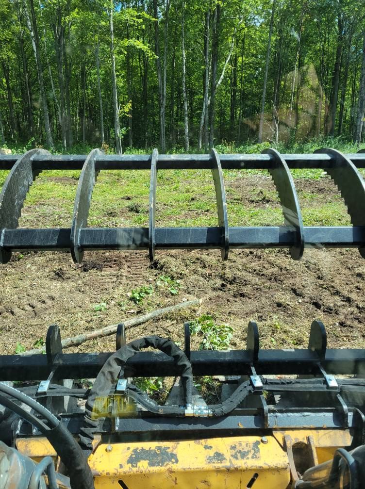 Yellow farm machinery in a field, with a wooded tree line in the background