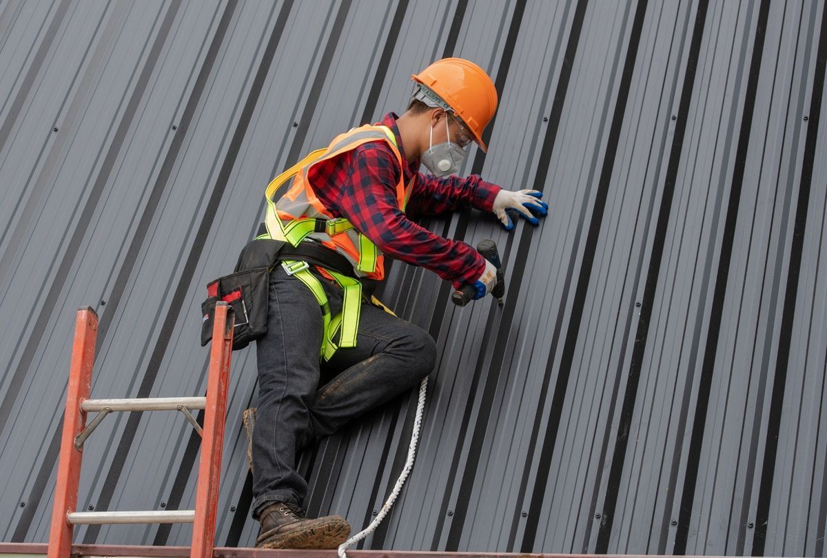 Roofing professionals wearing safety equipment on a residential roof in Los Banos