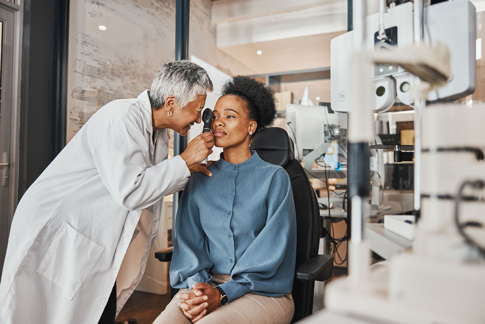 Woman at eye doctor, being examined with equipment, smiling.