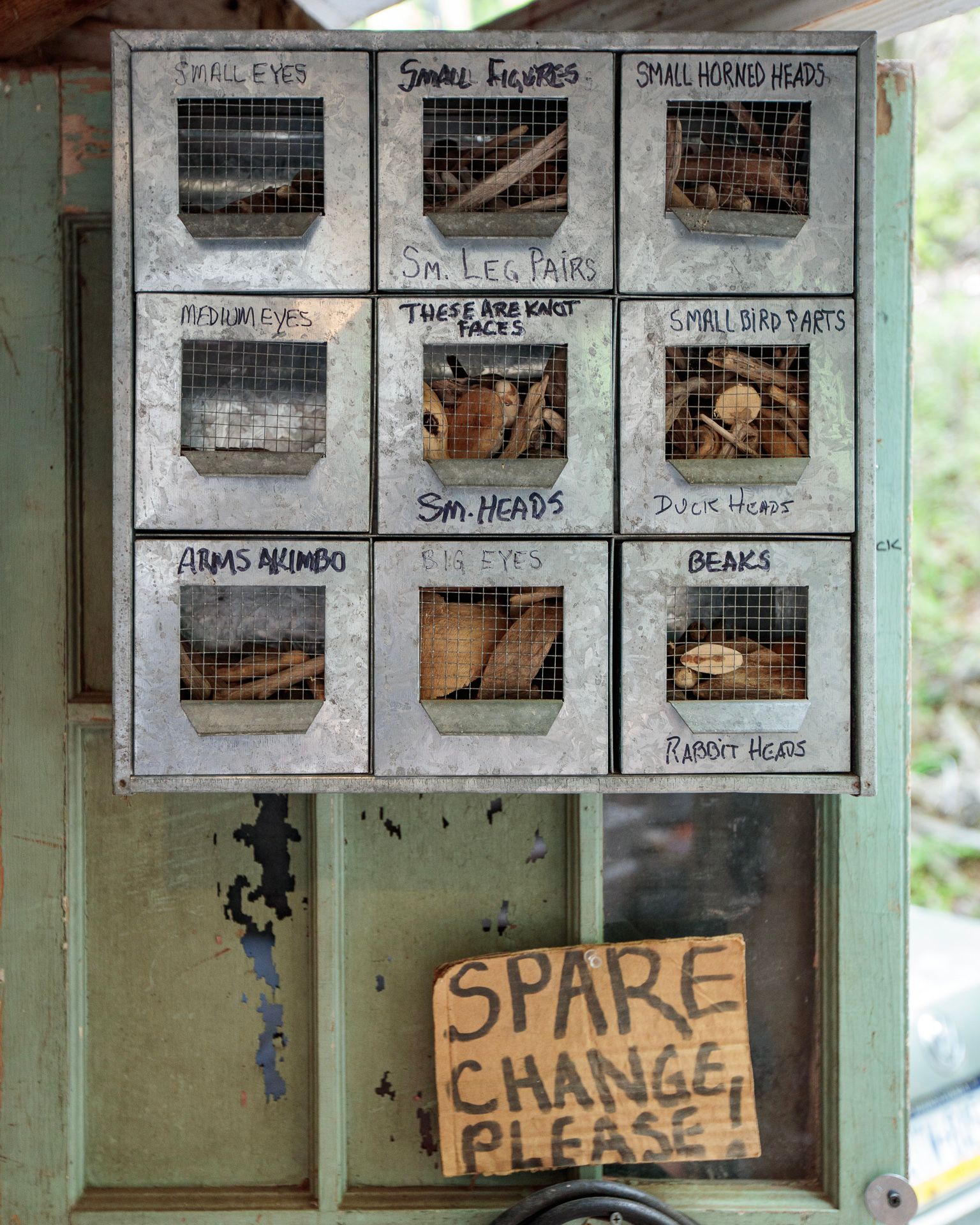 Handwritten menu board with food photos and a “SPARE CHANGE PLEASE” sign on a window
