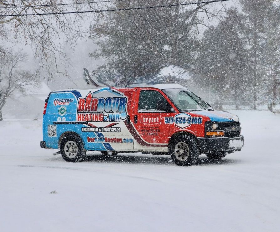 Colorful branded van driving through heavy snowfall on a snowy road, trees in the background