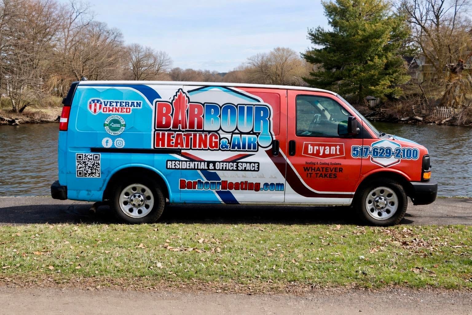 Parked Barber Heating & Cooling service van by a lakeside, with red, blue, and white graphics.