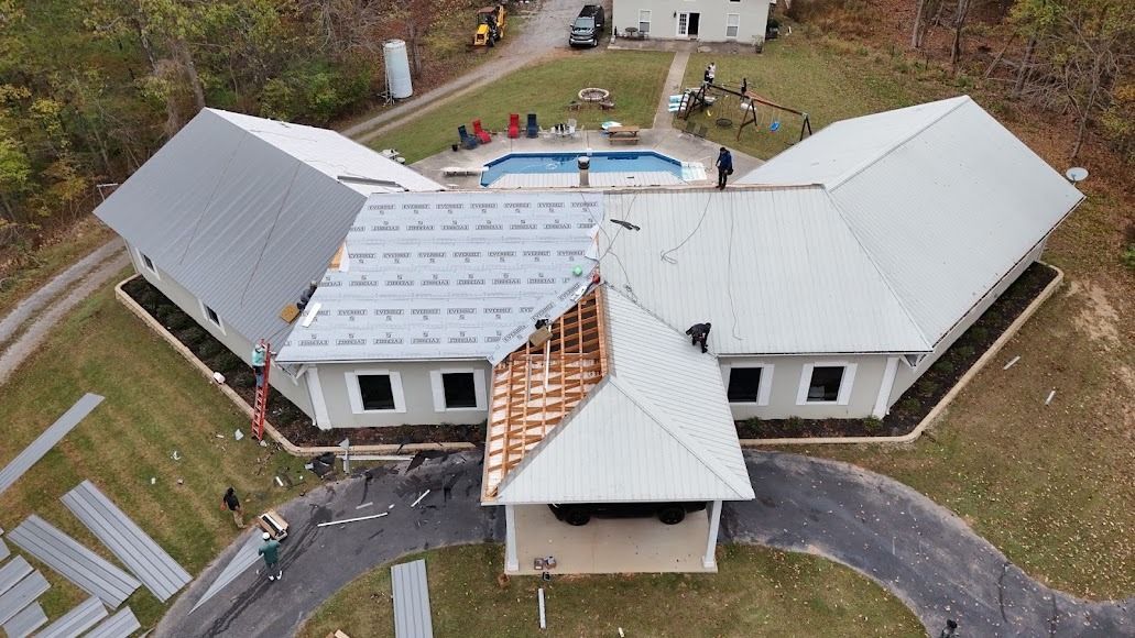 Aerial view of a white house with a damaged roof and a collapsed central porch area
