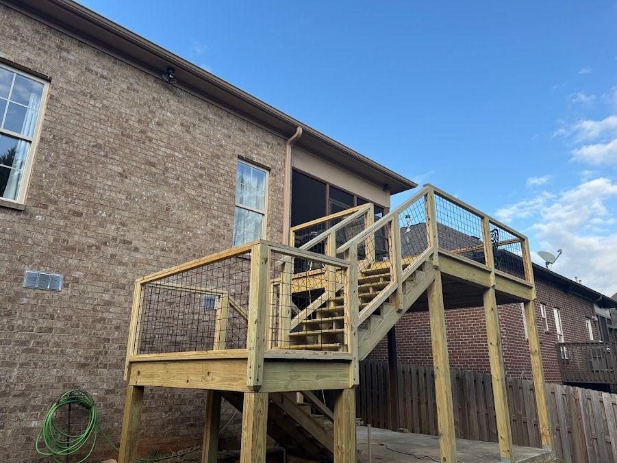 Wooden exterior staircase and deck attached to a brick house under a blue sky
