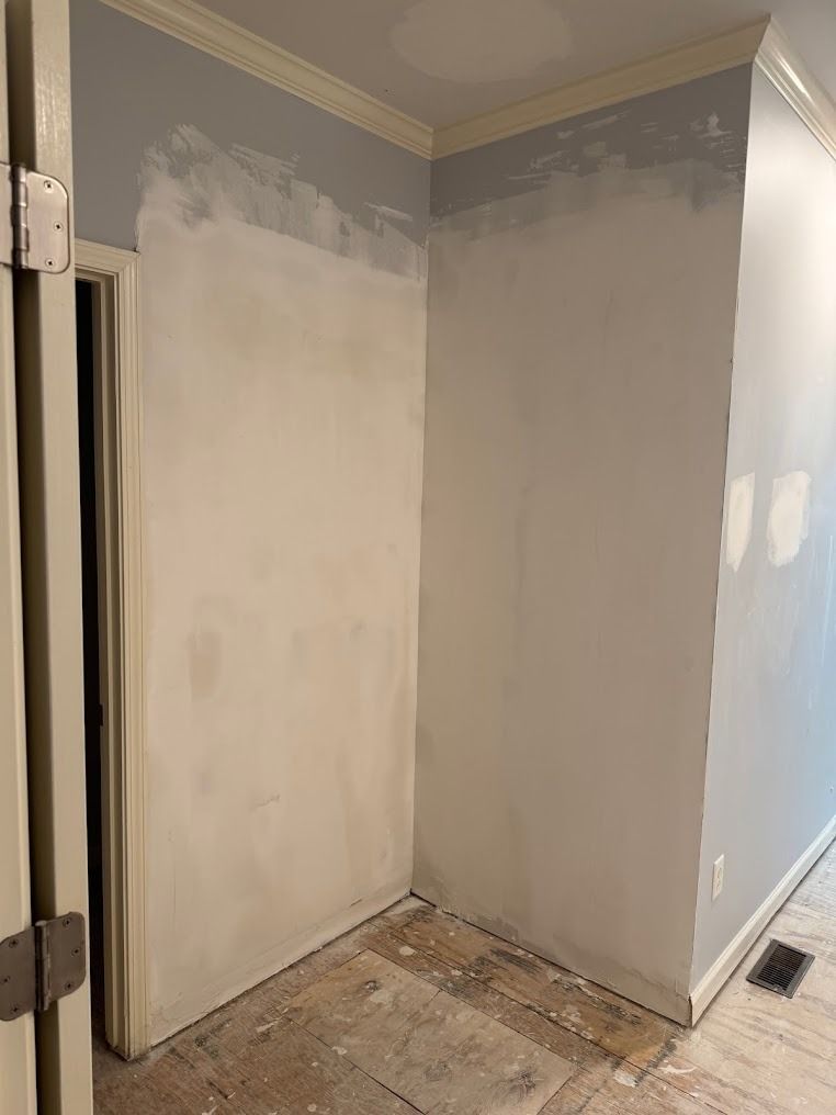 Partially painted empty room with gray and white walls and unfinished floor repairs